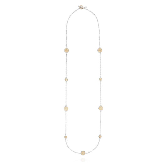 Long silver station necklace with alternating small and medium silver discs with gold dot details