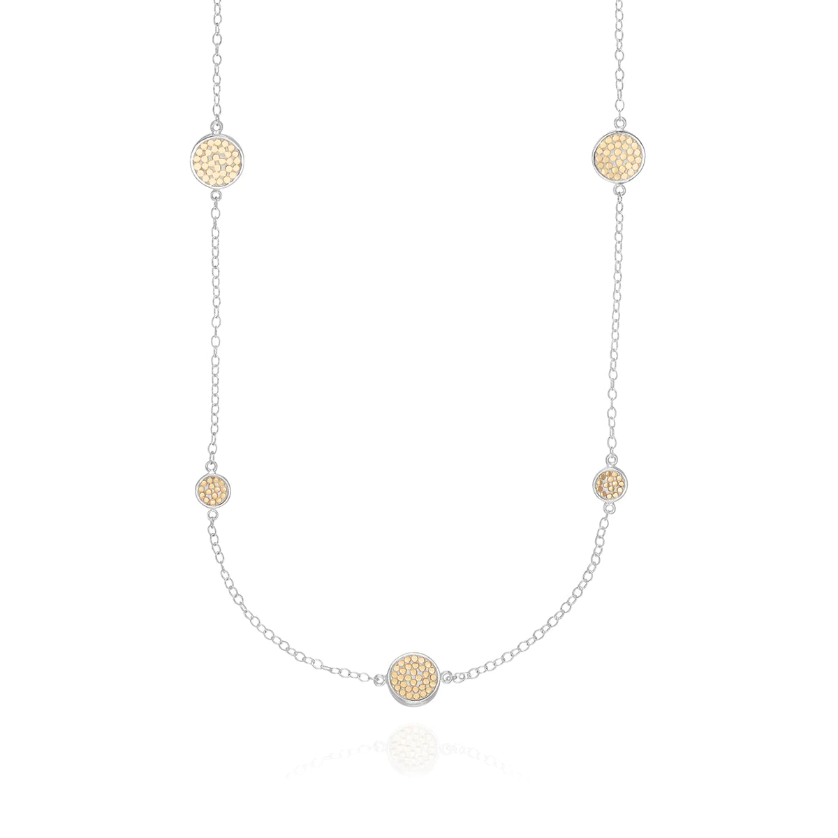 Long silver station necklace with alternating small and medium silver discs with gold dot details