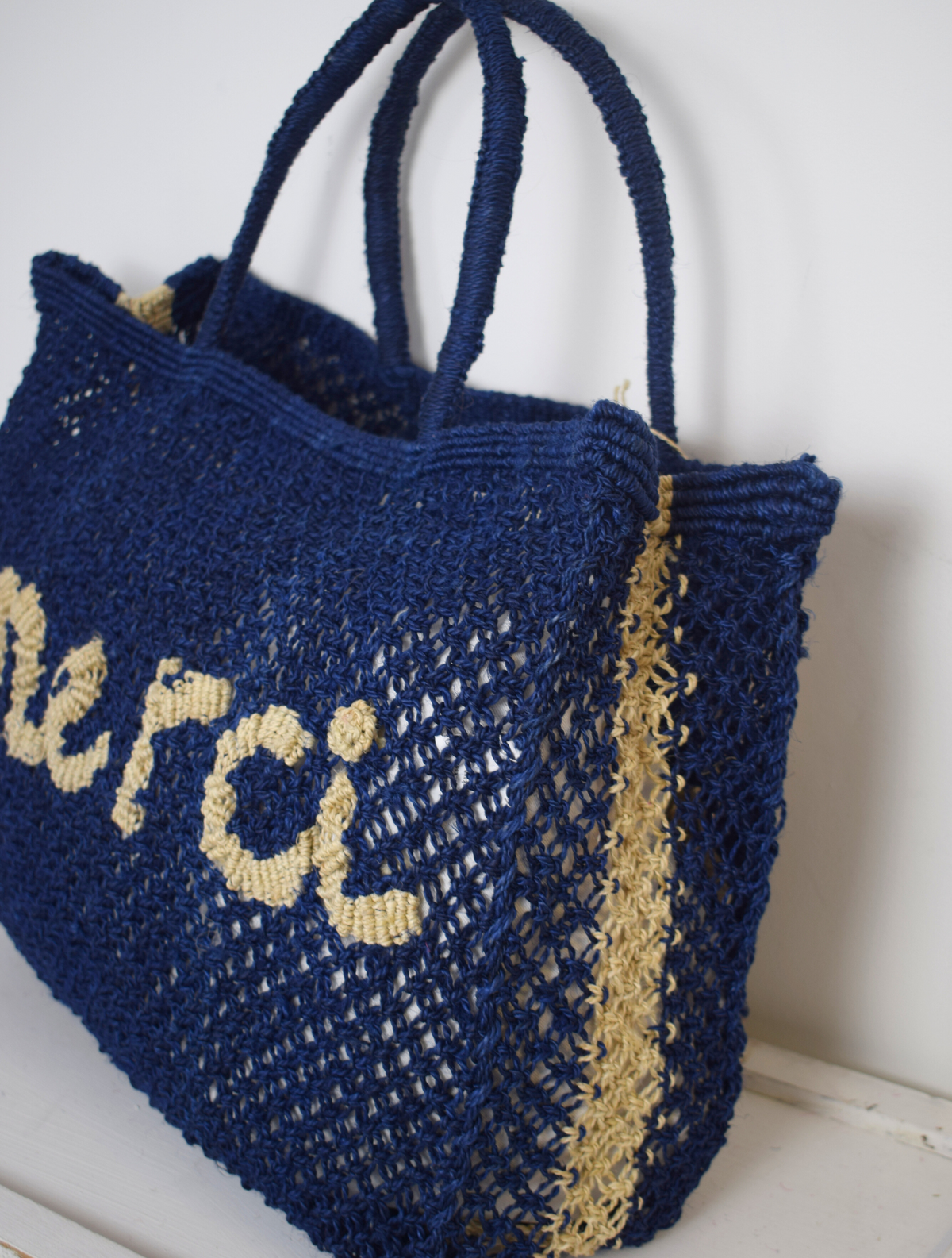 Blue woven bag with neautral writing on saying Merci