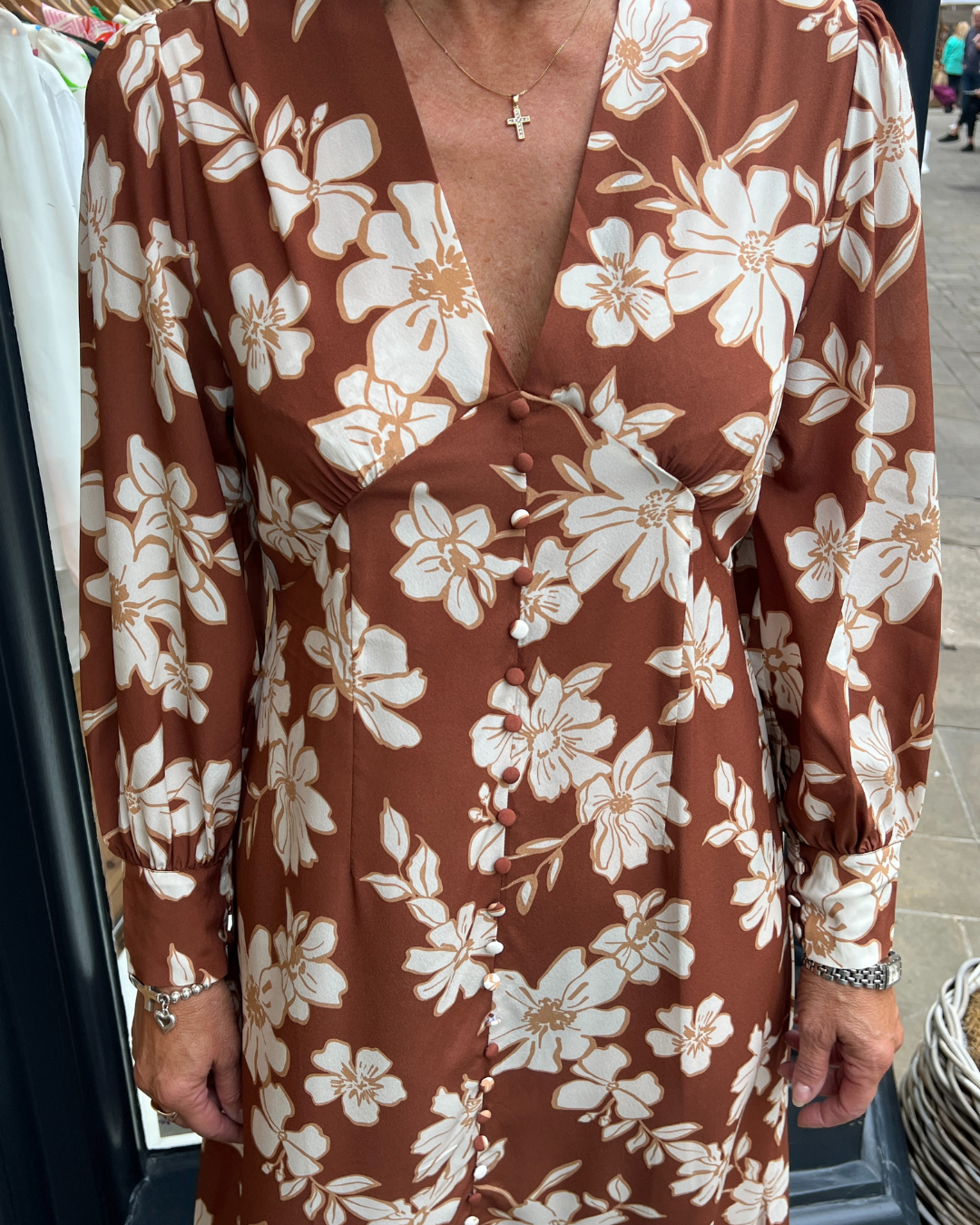 A long vintage style dress with a tan background and a white floral print 