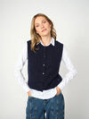 woman wearing a blue knit vest over a white shirt and blue jeans 