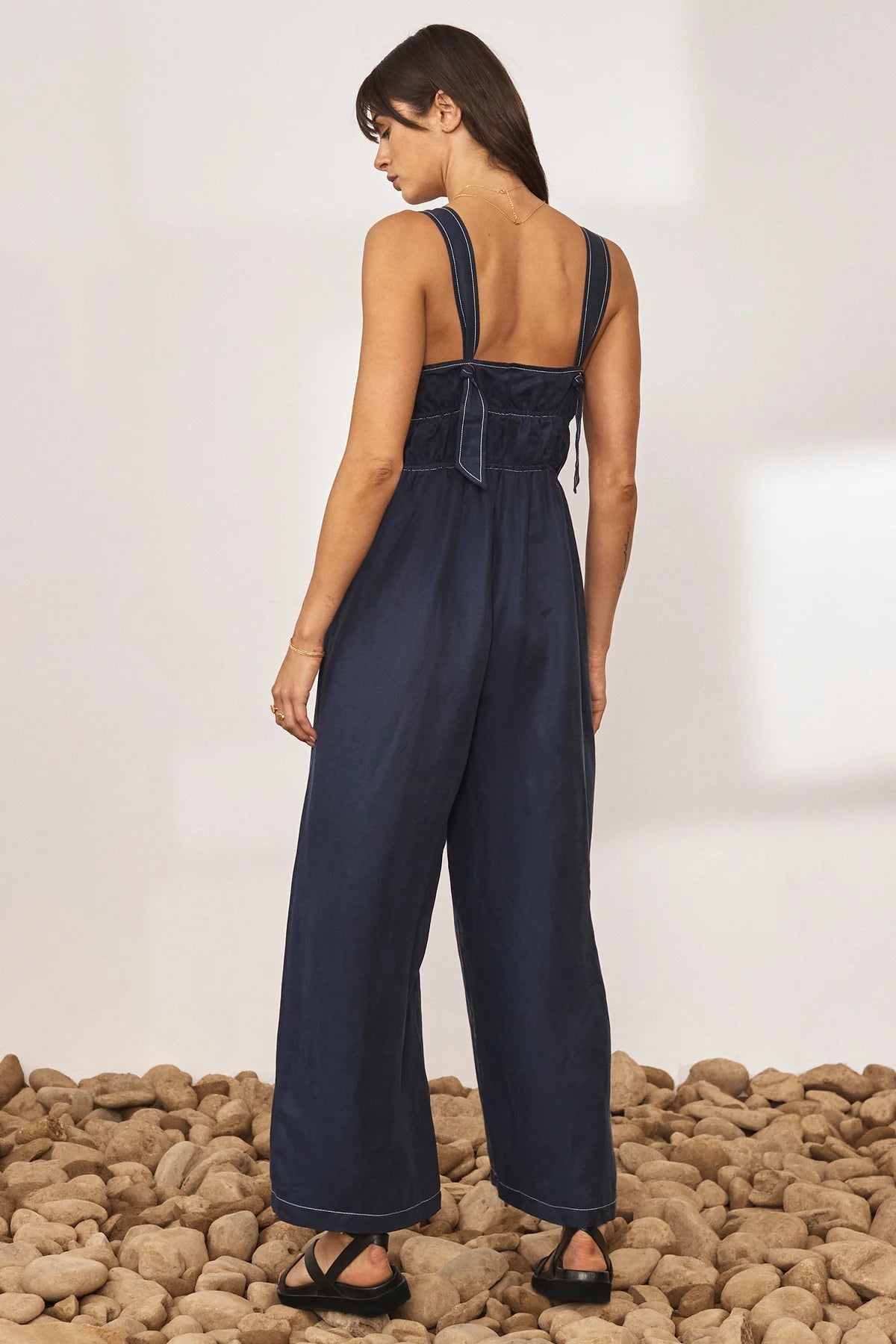 Navy wide leg jumpsuit with deep V neckline and thick tie straps at the back with white contrast stitching