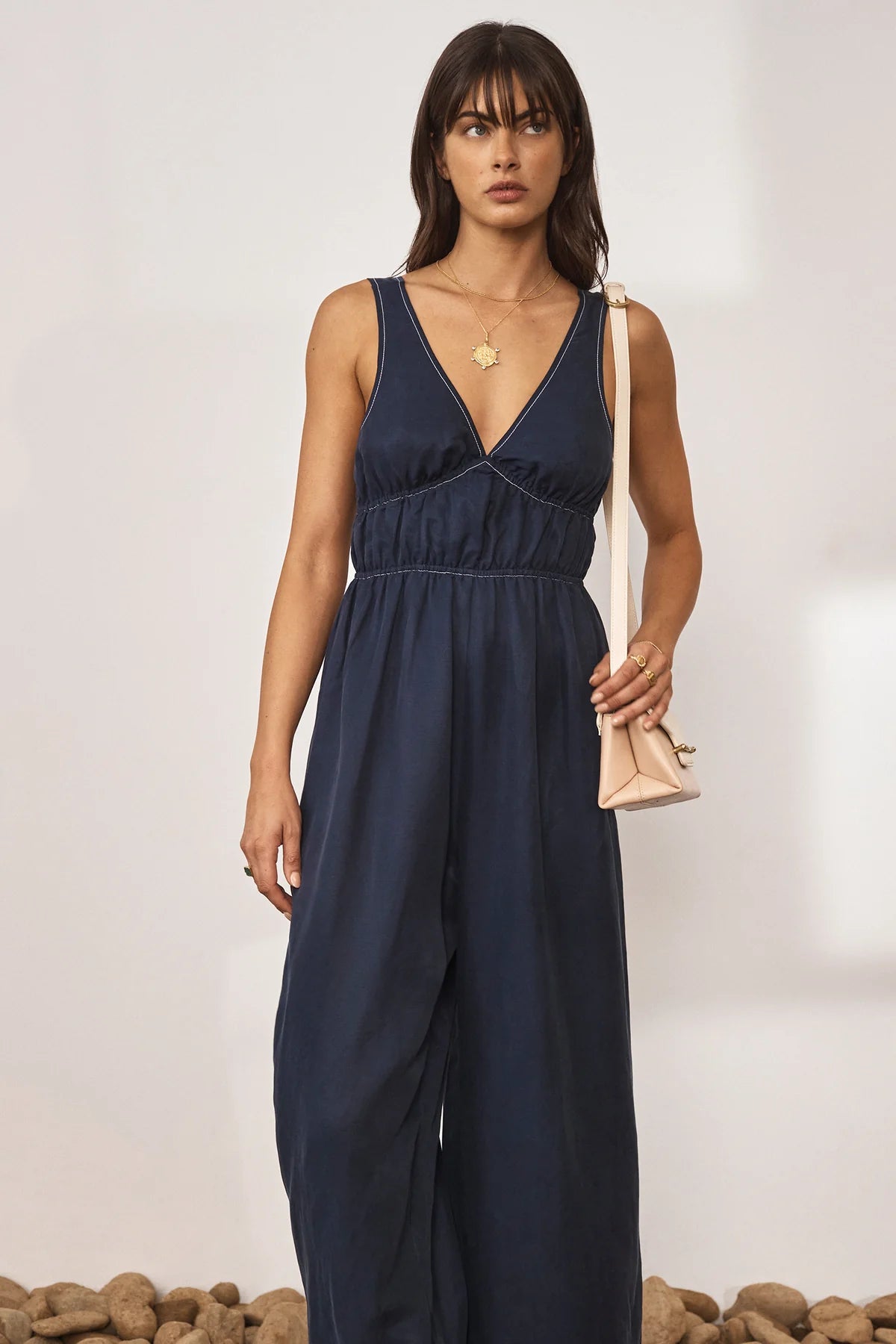 Navy wide leg jumpsuit with deep V neckline and thick tie straps at the back with white contrast stitching