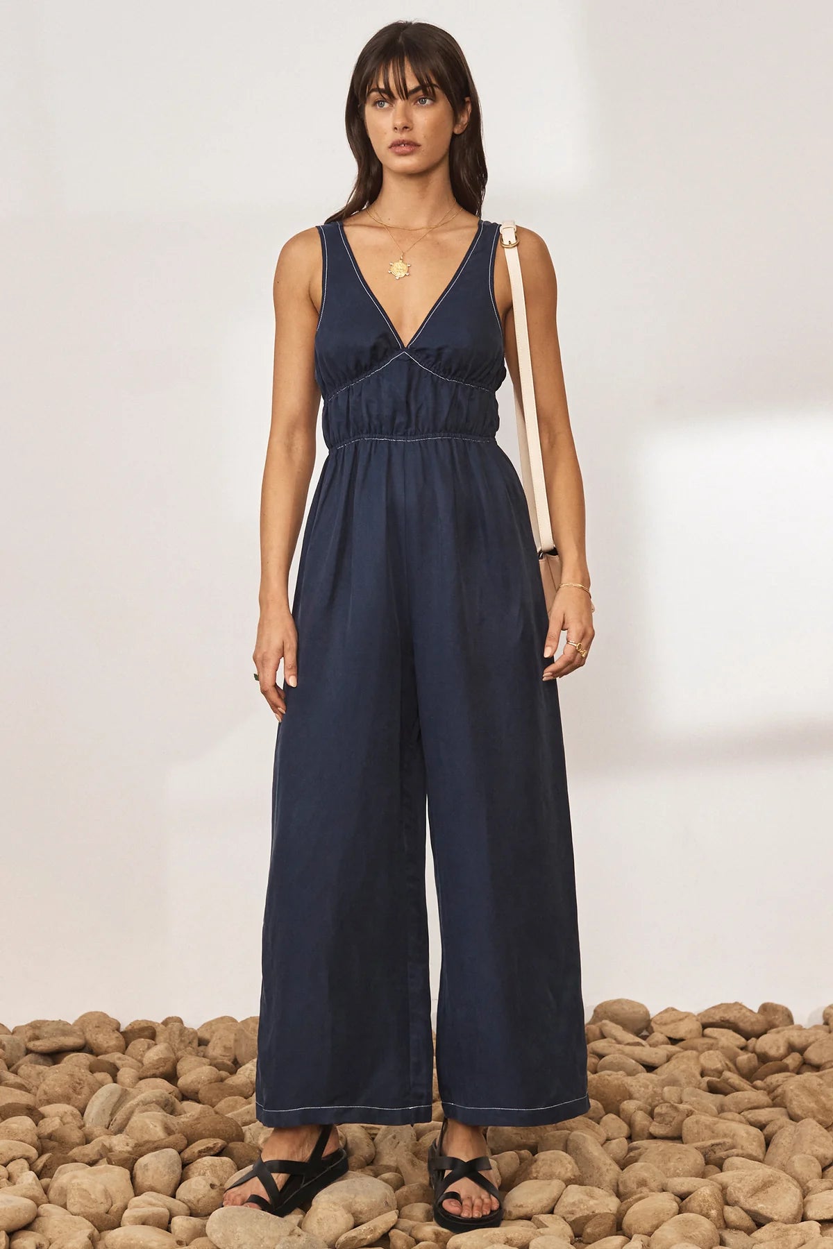 Navy wide leg jumpsuit with deep V neckline and thick tie straps at the back with white contrast stitching