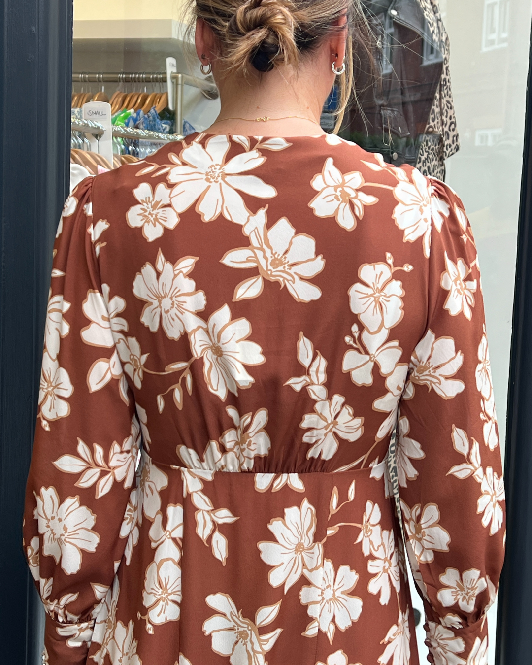 A long vintage style dress with a tan background and a white floral print 