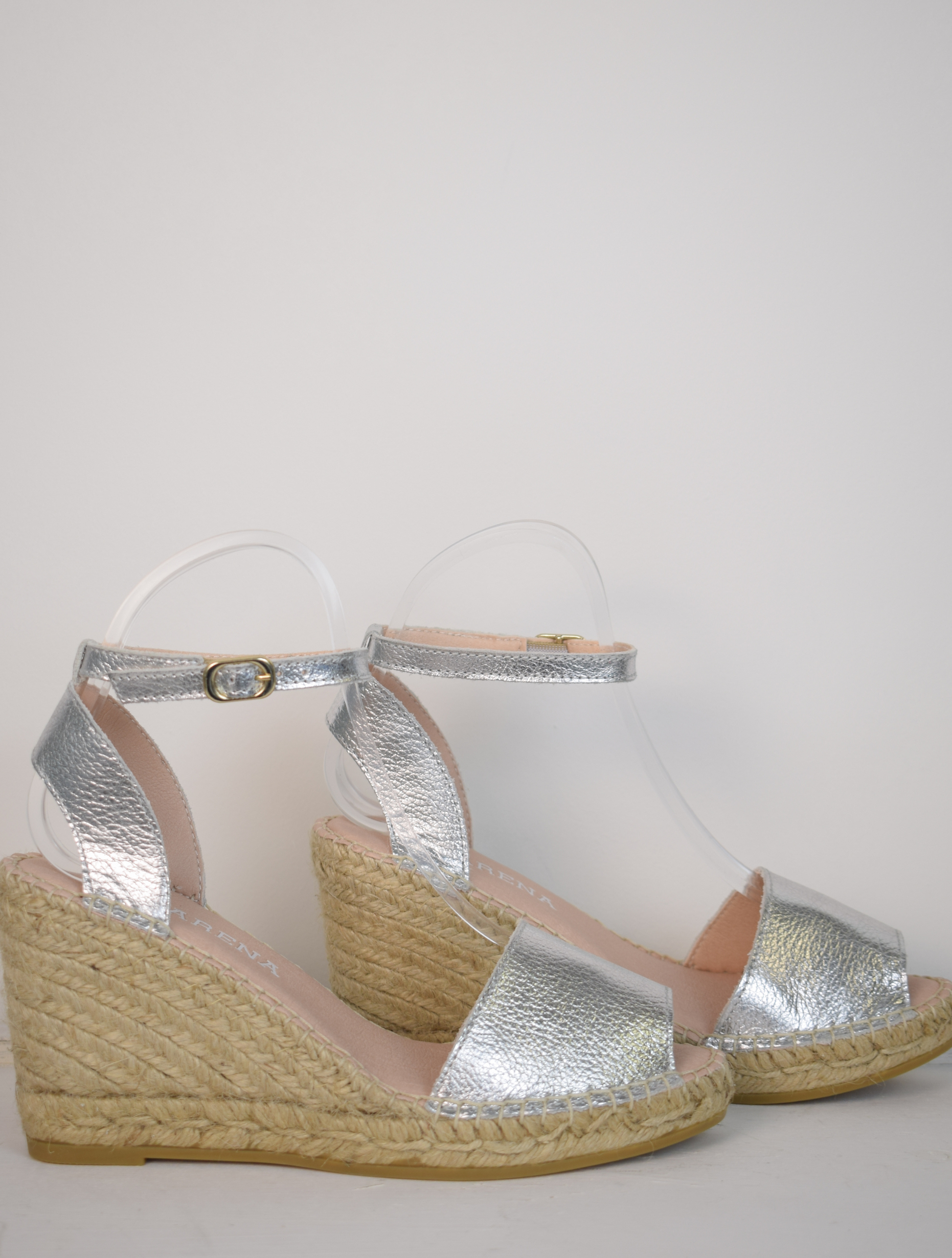 A silver wedge sandal with open toes and an ankle strap 