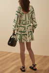 Short dress with long balloon sleeves with a green and gold print rear view