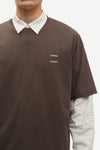 Man wearing a Brown Samsoe Samsoe T shirt over a shirt close up