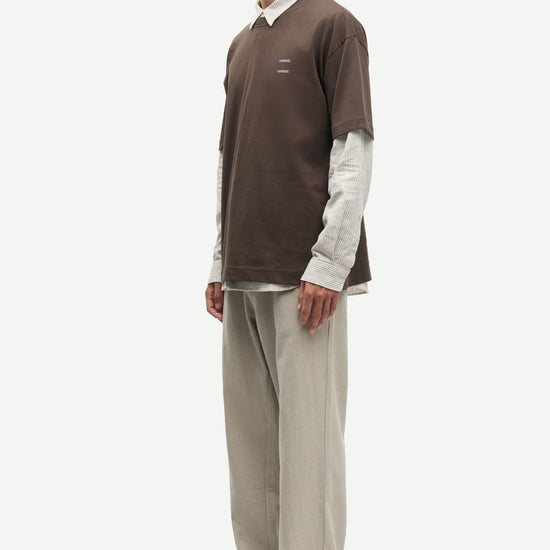 Man wearing a Brown Samsoe Samsoe T shirt over a shirt side view