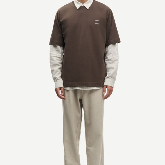 Man wearing a Brown Samsoe Samsoe T shirt over a shirt front view