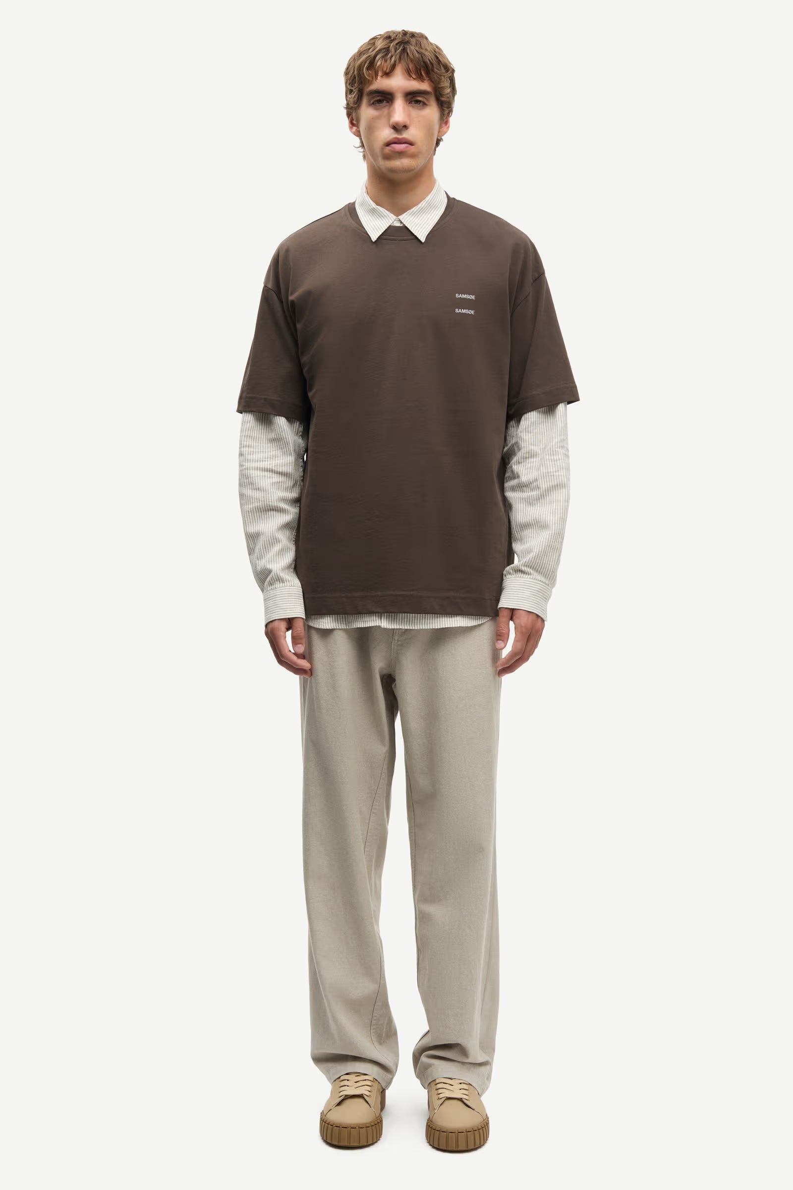 Man wearing a Brown Samsoe Samsoe T shirt over a shirt front view
