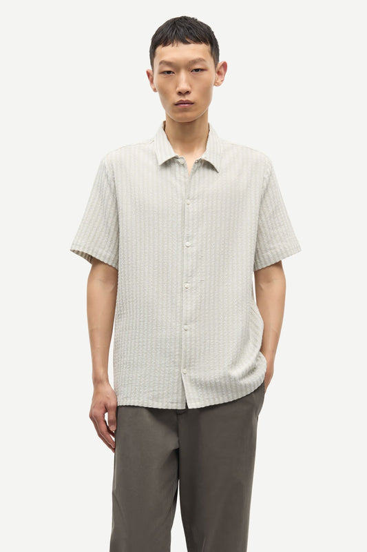 Man wearing a light-colored checkered shirt and gray pants on a white background