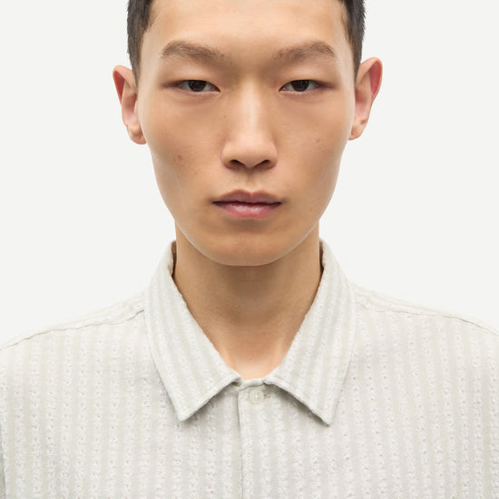 Man wearing a light-colored shirt against a plain background