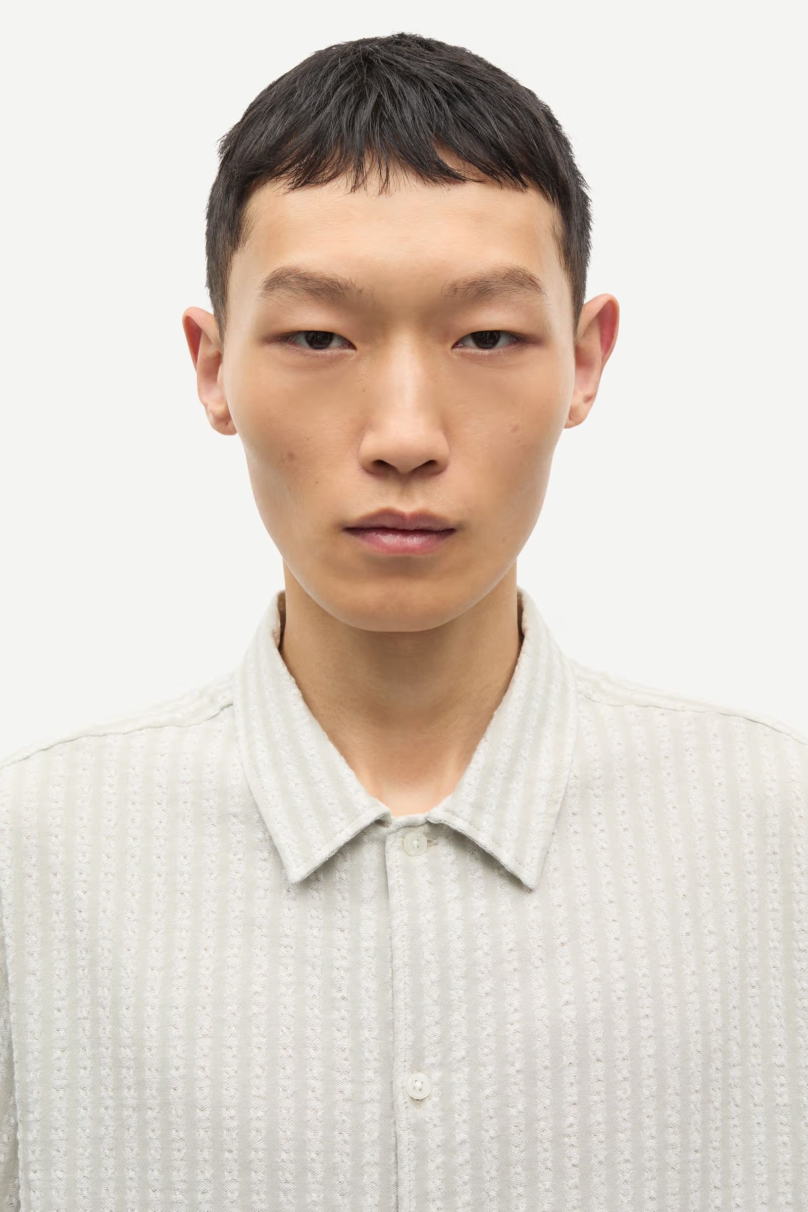 Man wearing a light-colored shirt against a plain background