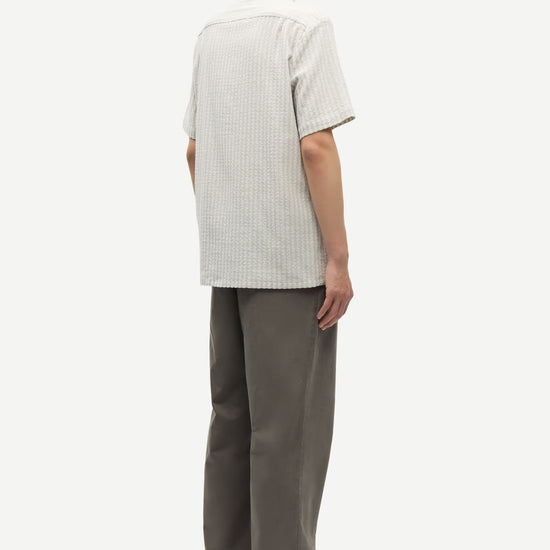 Person wearing a light-colored shirt and dark pants on a white background