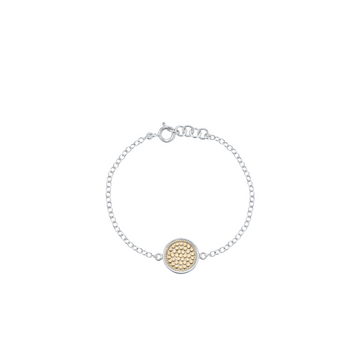 A delicate silver chain bracelet with a central round gold-tone textured disc charm, displayed on a clean white background.