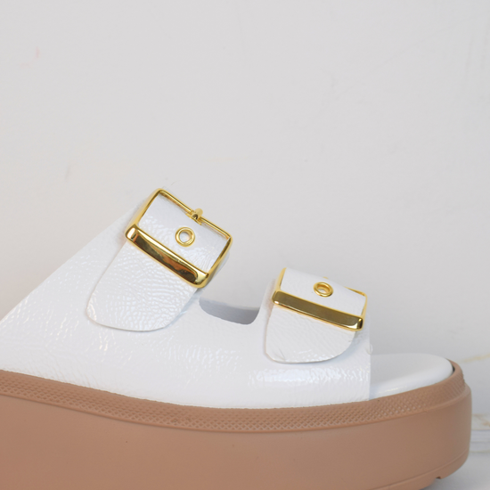 White platform slider with double strap gold metallic buckles and taupe coloured rubber platform sole