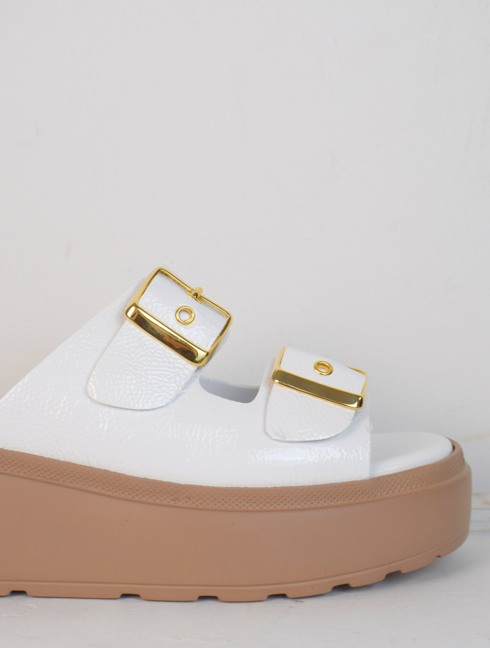 White platform slider with double strap gold metallic buckles and taupe coloured rubber platform sole