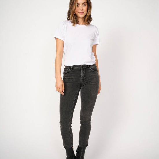 Woman wearing a white t-shirt and grey jeans on a white background