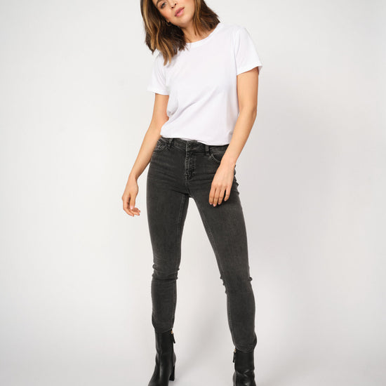 Woman wearing a white t-shirt and grey jeans on a white background