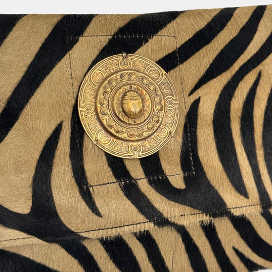 zebra fold over bag with gold emblum and rivet strap close up