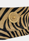 zebra fold over bag with gold emblum and rivet strap close up