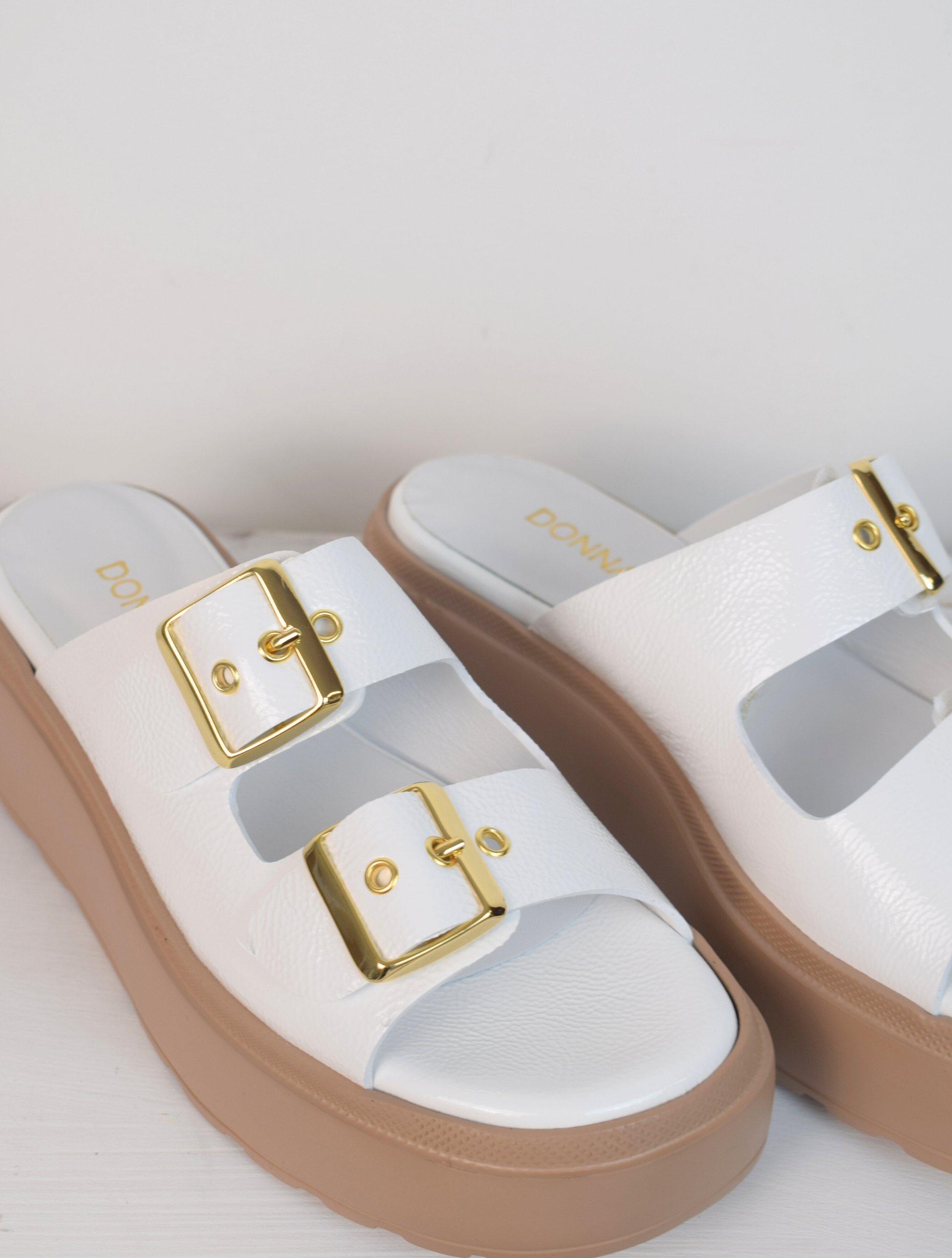 White platform slider with double strap gold metallic buckles and taupe coloured rubber platform sole