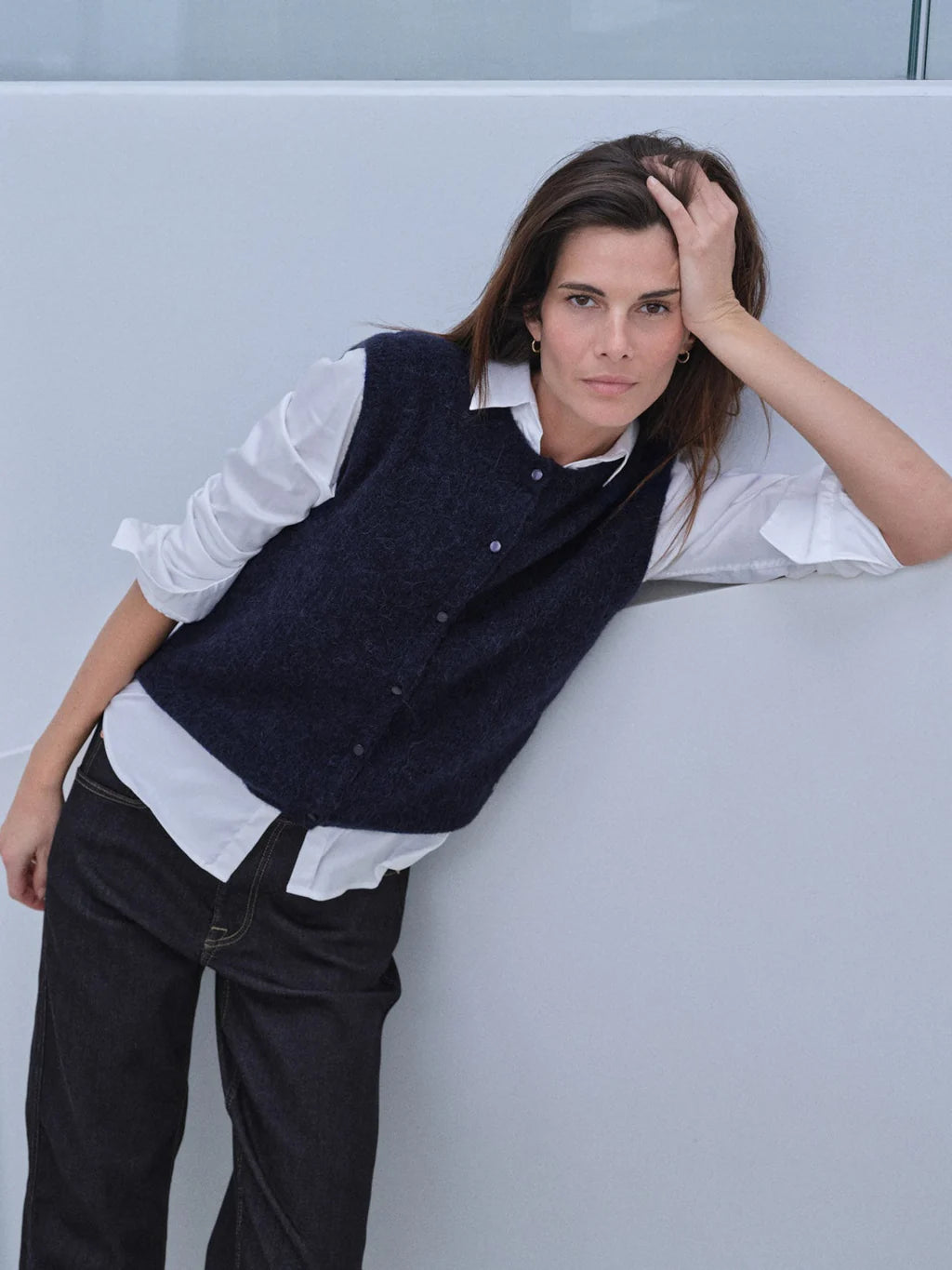 woman wearing a blue knit vest over a white shirt and jeans 