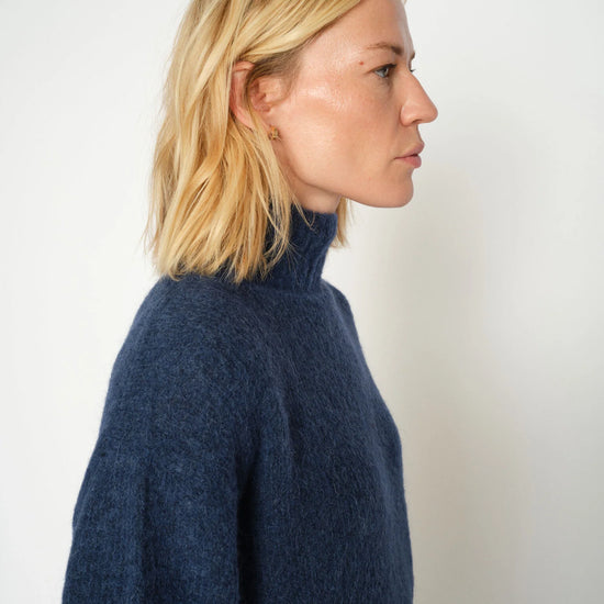 Side view of model wearing a blue high neck knit from Mos Mosh