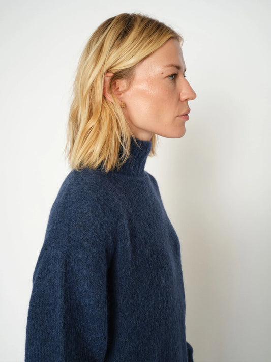Side view of model wearing a blue high neck knit from Mos Mosh