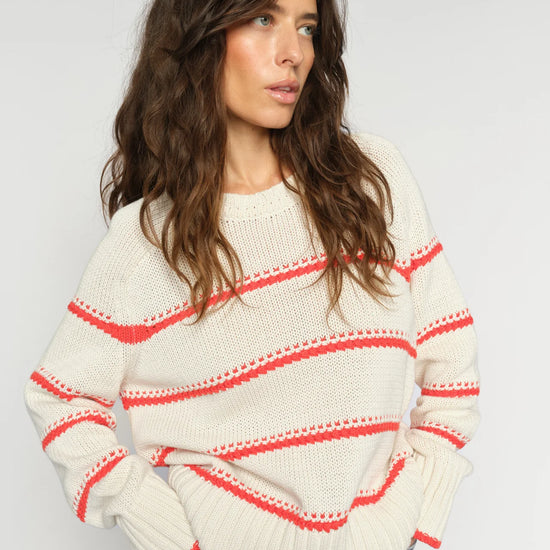 model wearing cream jumper with orange stripes on it 