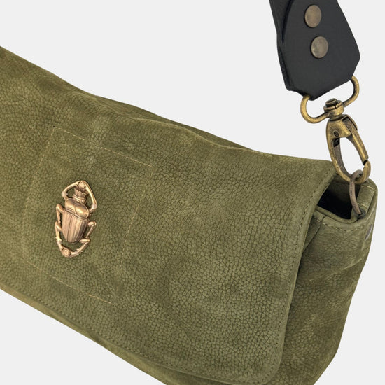 green nubuck leather fold over bag with gold scarab detail and rivet strap close up