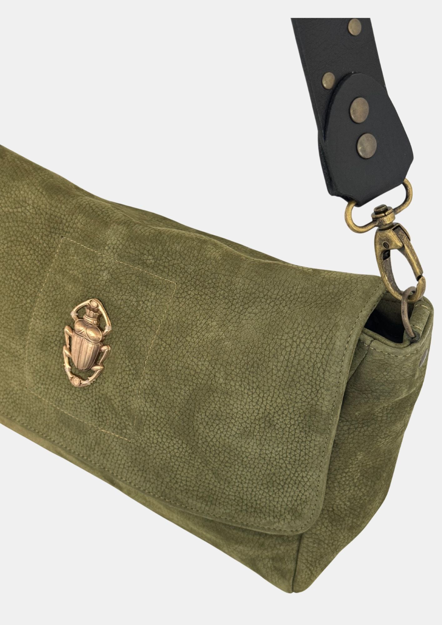 green nubuck leather fold over bag with gold scarab detail and rivet strap close up