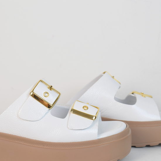 White platform slider with double strap gold metallic buckles and taupe coloured rubber platform sole