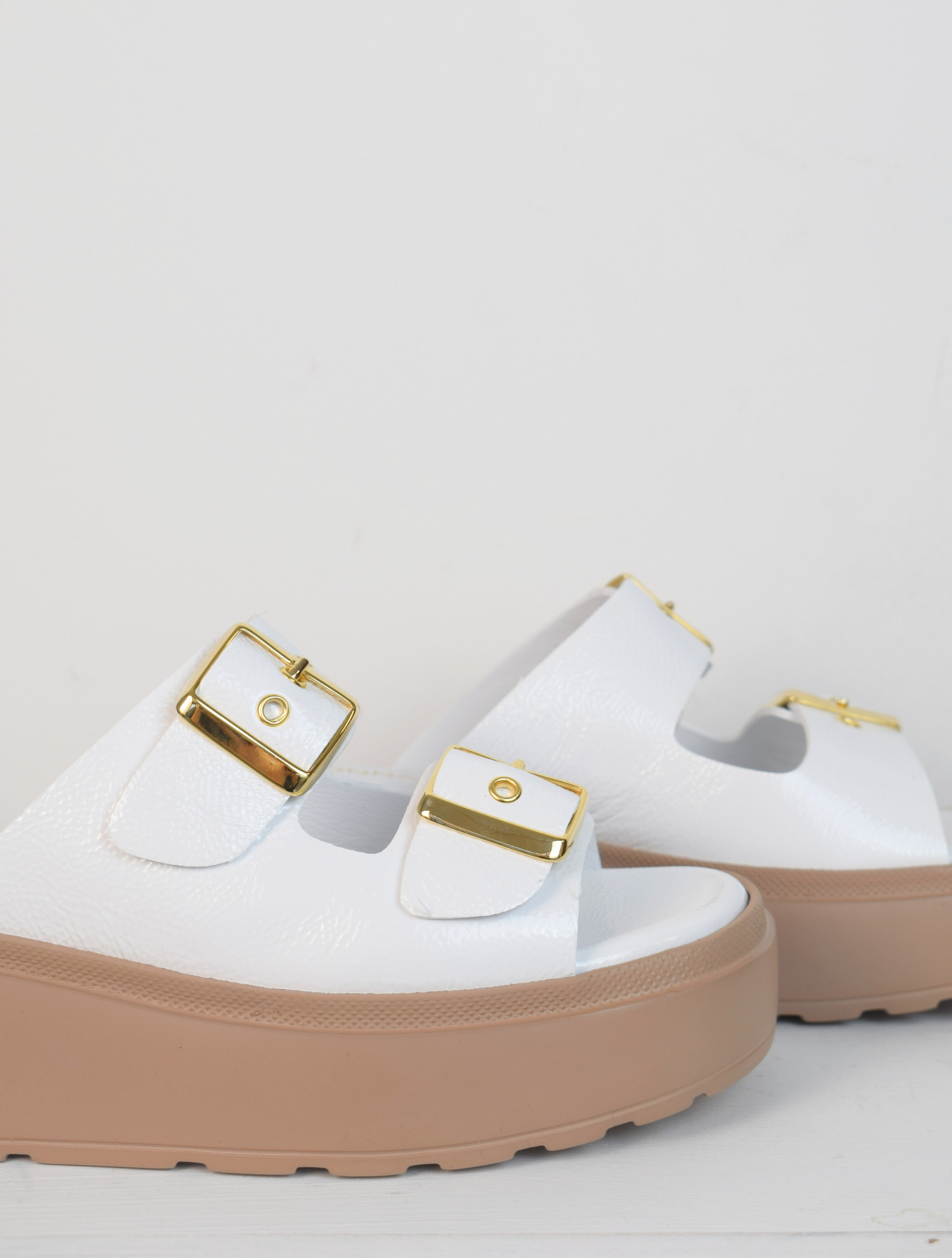 White platform slider with double strap gold metallic buckles and taupe coloured rubber platform sole