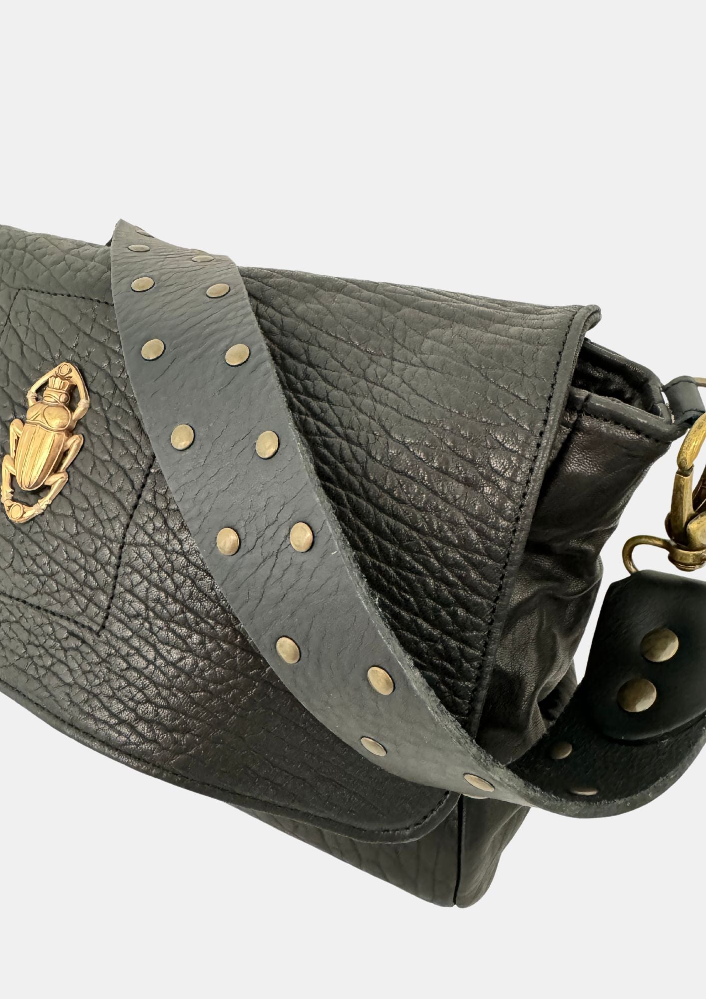 black lamb leather fold over bag with rivet strap and gold scarab emblum close up