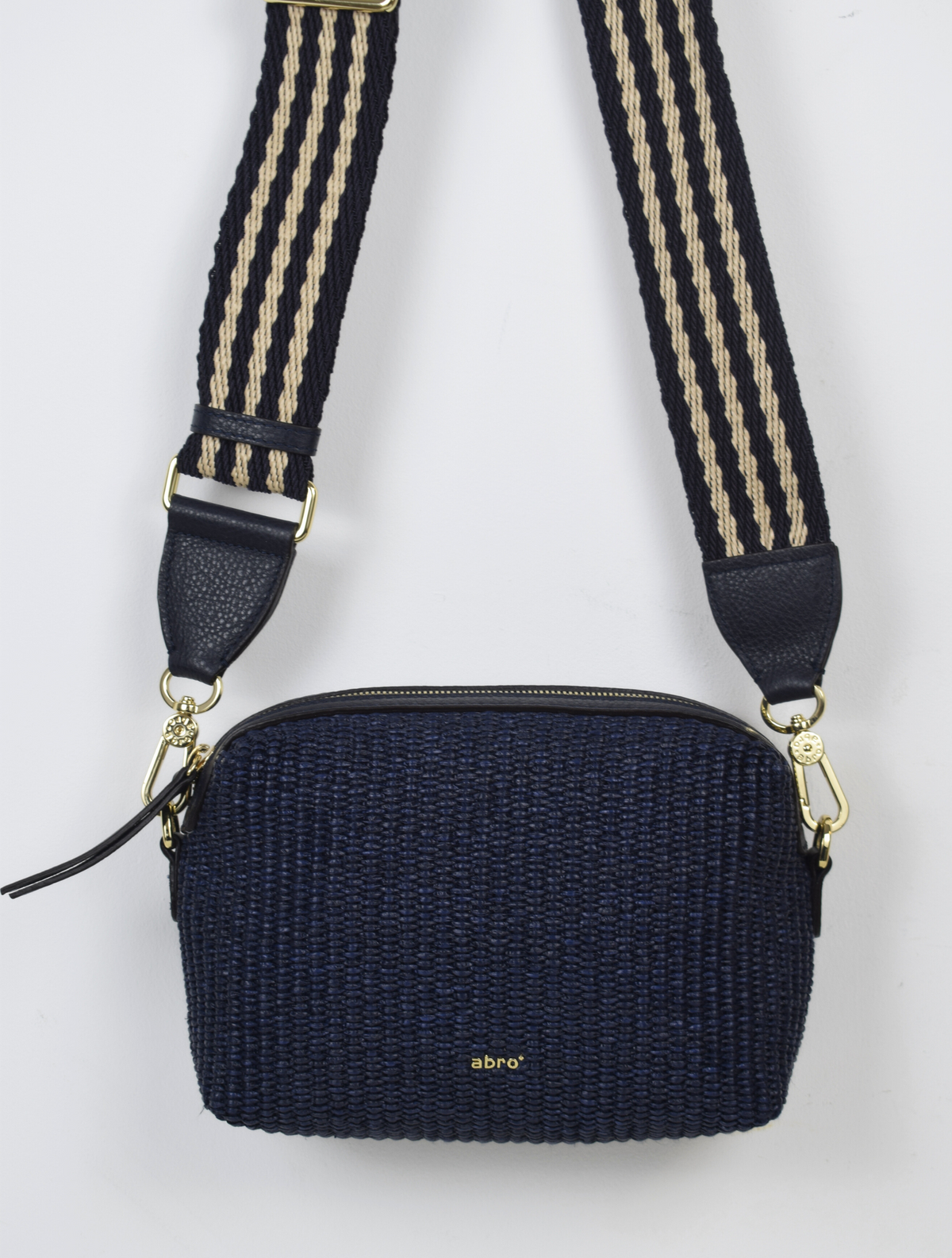A navy raffia bag with a stripe strap. 