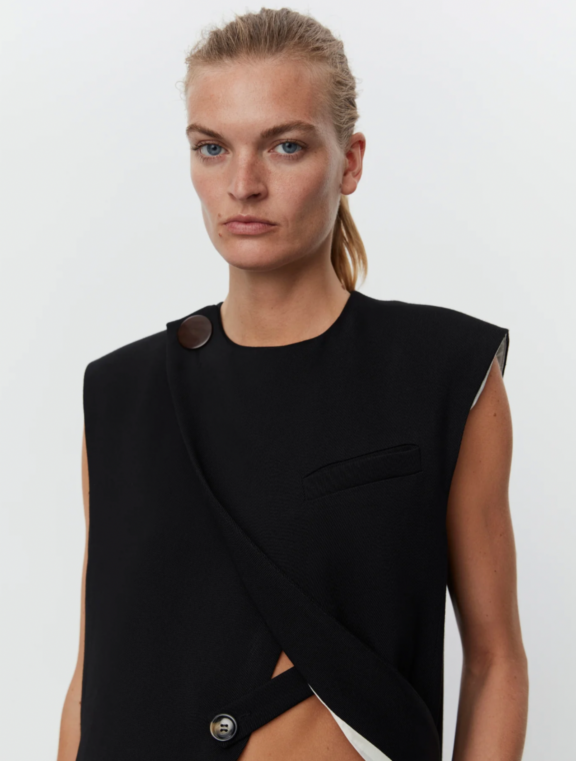 Black asymmetric waistcoat with large button on right shoulder and centre rear vent