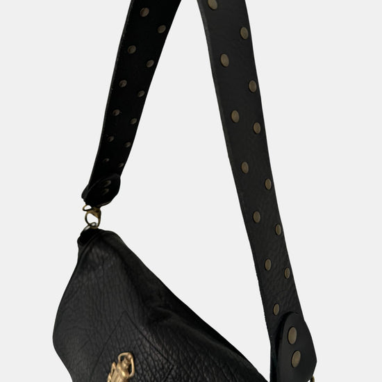 black lamb leather fold over bag with rivet strap and gold scarab emblum close up of strap