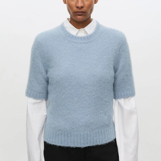 Pale blue short sleeve knit worn over white shirt with black trousers