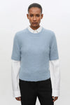 Pale blue short sleeve knit worn over white shirt with black trousers
