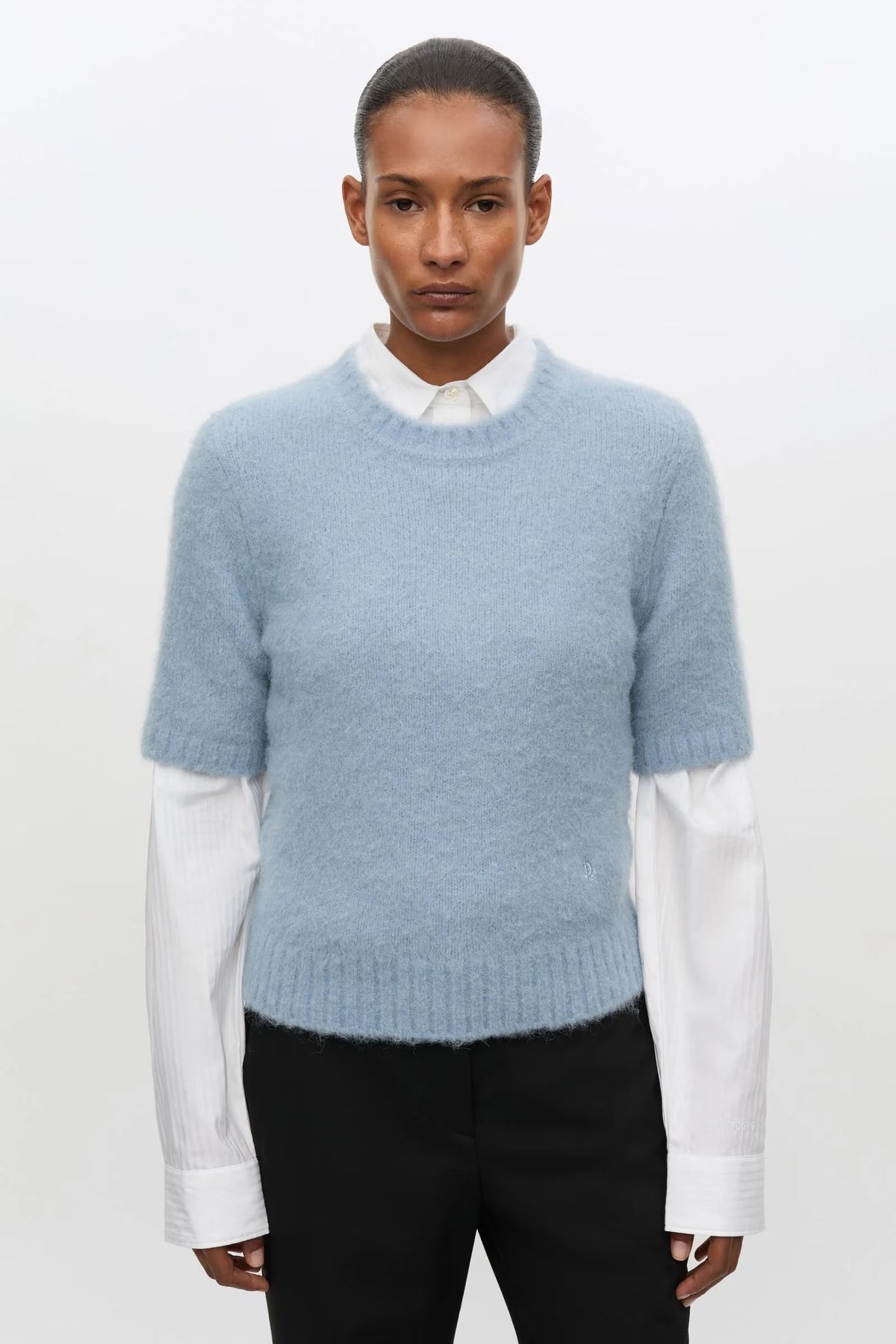 Pale blue short sleeve knit worn over white shirt with black trousers