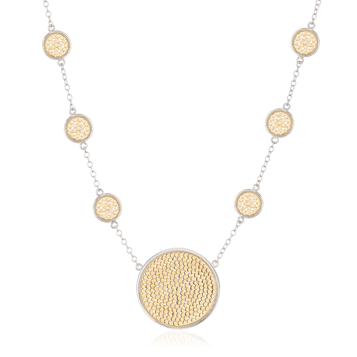 Gold and silver station necklace with small circular dotted discs and a large central disc with mutliple small gold dots