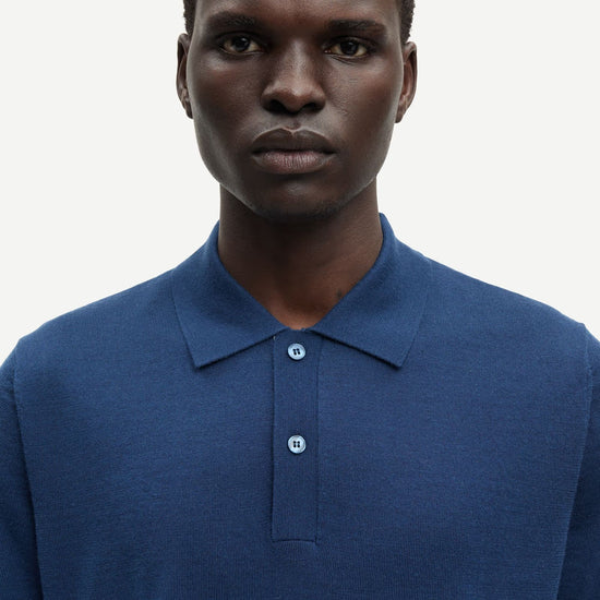 Man wearing a blue polo shirt against a white background