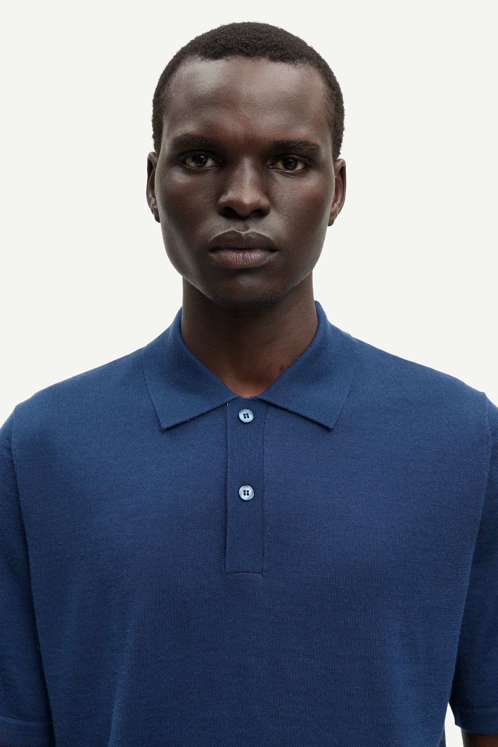 Man wearing a blue polo shirt against a white background