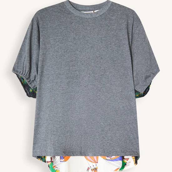 A heather gray short-sleeve t-shirt with a high-low hemline and a colorful abstract pattern lining the hem and sleeve cuffs, displayed against a light off-white background.