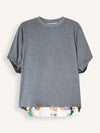 A heather gray short-sleeve t-shirt with a high-low hemline and a colorful abstract pattern lining the hem and sleeve cuffs, displayed against a light off-white background.