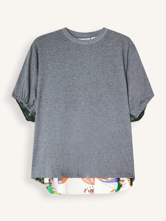 A heather gray short-sleeve t-shirt with a high-low hemline and a colorful abstract pattern lining the hem and sleeve cuffs, displayed against a light off-white background.
