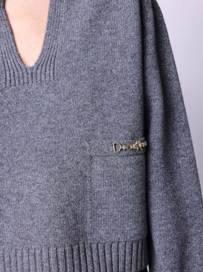 Grey v-neck jumper with 2 front pockets pockets and gold buckle detailing close up