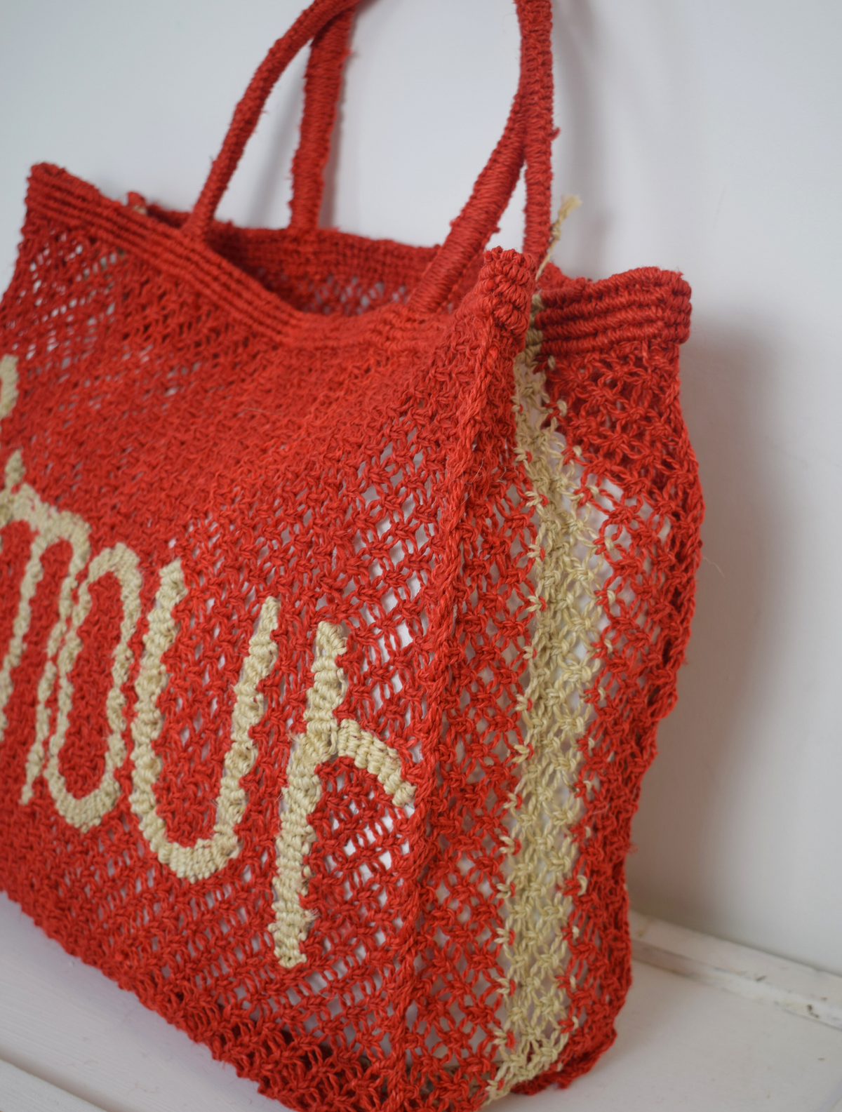 red woven bag with nude writing on saying Amour